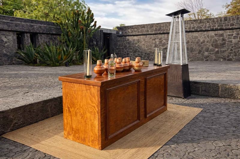 Montaje de barra de servicio en exterior con mobiliario de madera de alta gama, ambientación cálida y elementos decorativos para eventos sociales o corporativos en espacio abierto